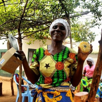 Photo 6: A member of the Tumaini women’s group proudly displays the solar lamp she just received.